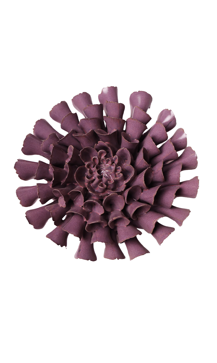 A single sculptural flower-shaped product in a muted plum-purple color, photographed from above on a plain white background.