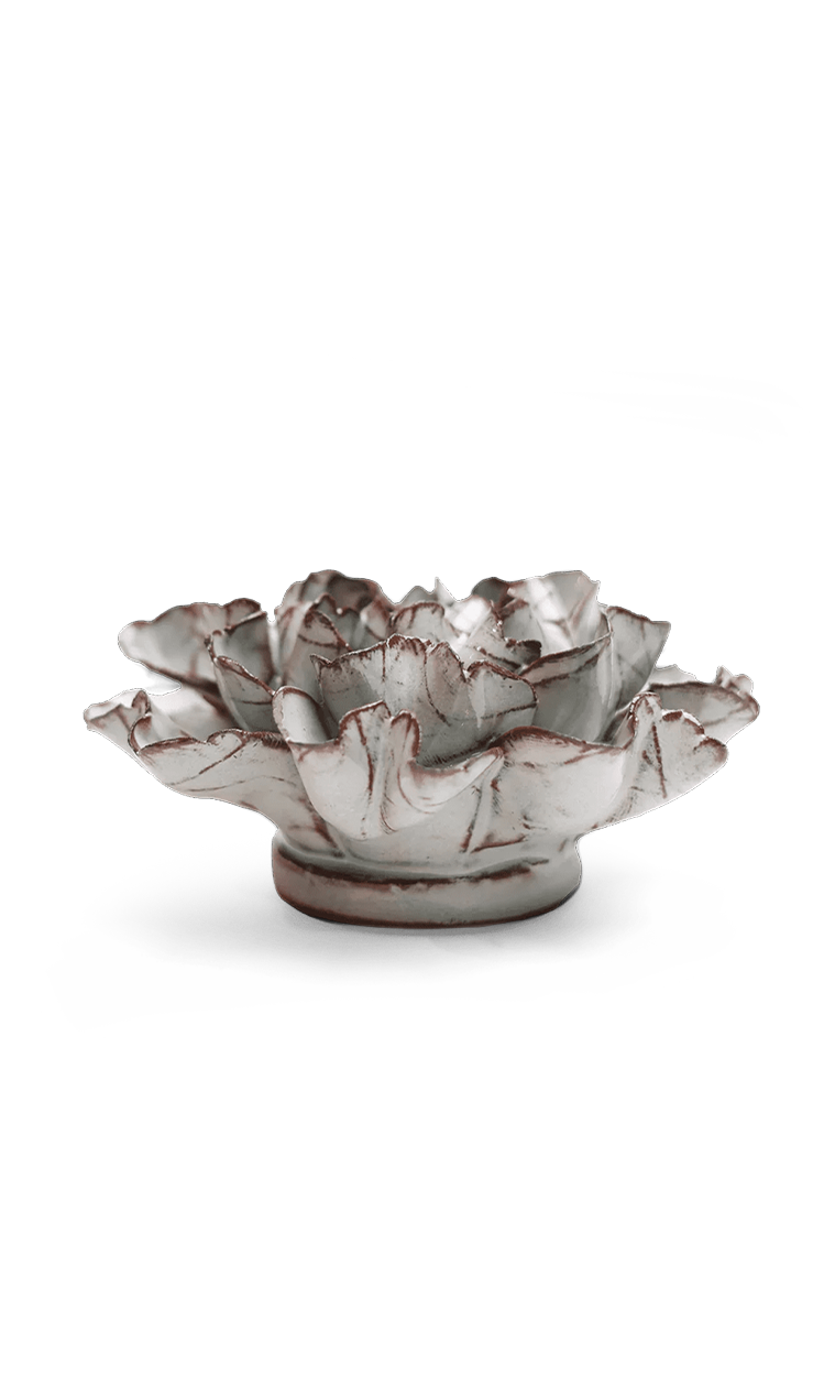 A sculptural ceramic lotus flower bowl with a textured, weathered finish in off-white and gray with subtle reddish-brown accents along the petal edges, set against a plain white background.