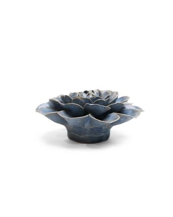 A small sculptural flower-shaped object with layered petals, shown on a clean white background. The item has a glossy dark blue glaze with lighter blue-gray highlights and a slightly distressed, rustic finish.
