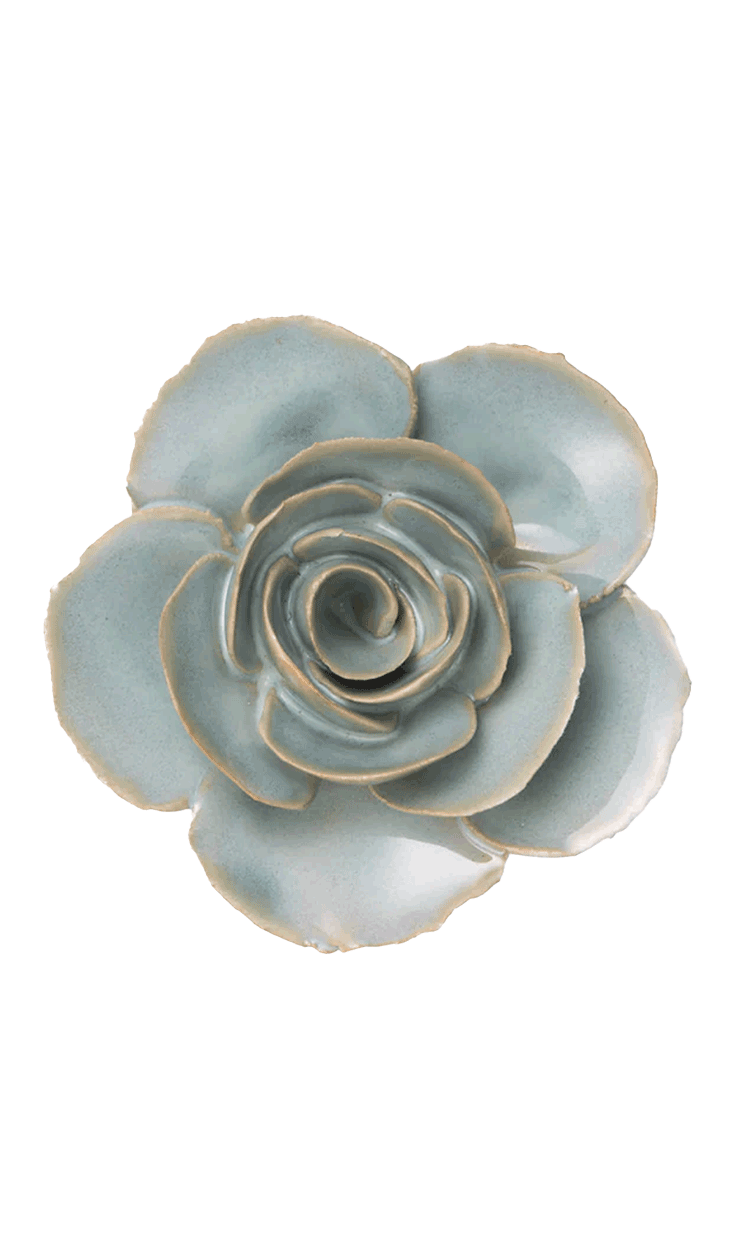 A ceramic succulent-style flower figurine with pale blue-green glazed petals and natural clay edges, photographed from directly above on a plain white background.