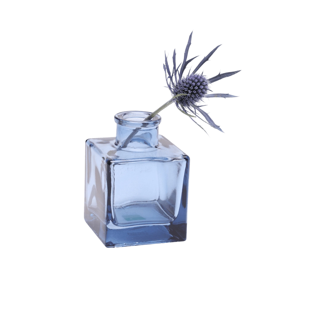 Chive Loft cube glass bud vase in medium blue styled with a single blue thistle stem.