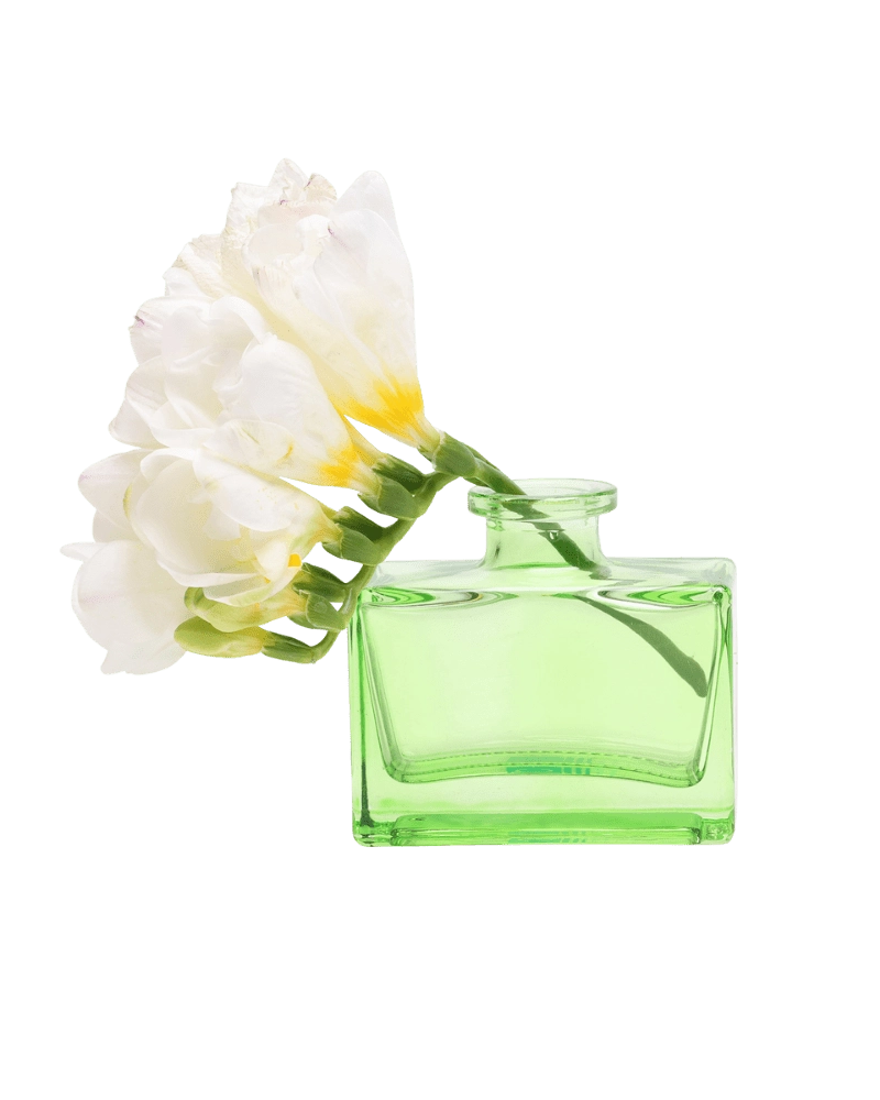Chive Loft square glass bud vase in green holding freesia blooms, shown from a side angle.