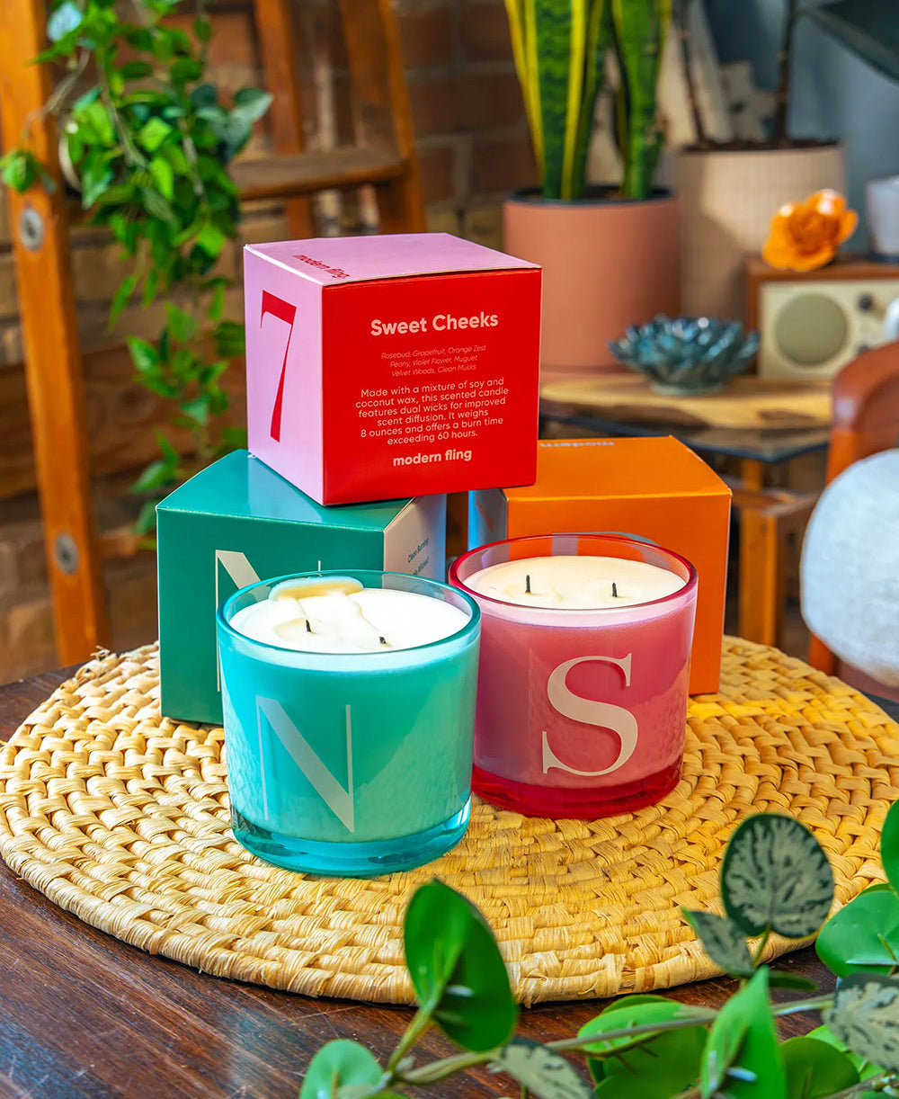 Two Chive Modern Fling teal nectar and pink sweet cheeks coconut soy medium candles styled with packaging boxed in a home setting.
