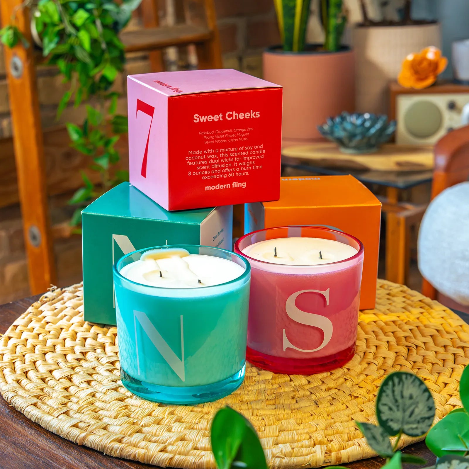Two Chive Modern Fling teal nectar and pink sweet cheeks coconut soy medium candles styled with packaging boxed in a home setting.
