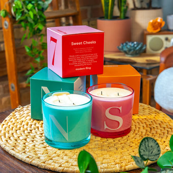 Two Chive Modern Fling teal nectar and pink sweet cheeks coconut soy medium candles styled with packaging boxed in a home setting.