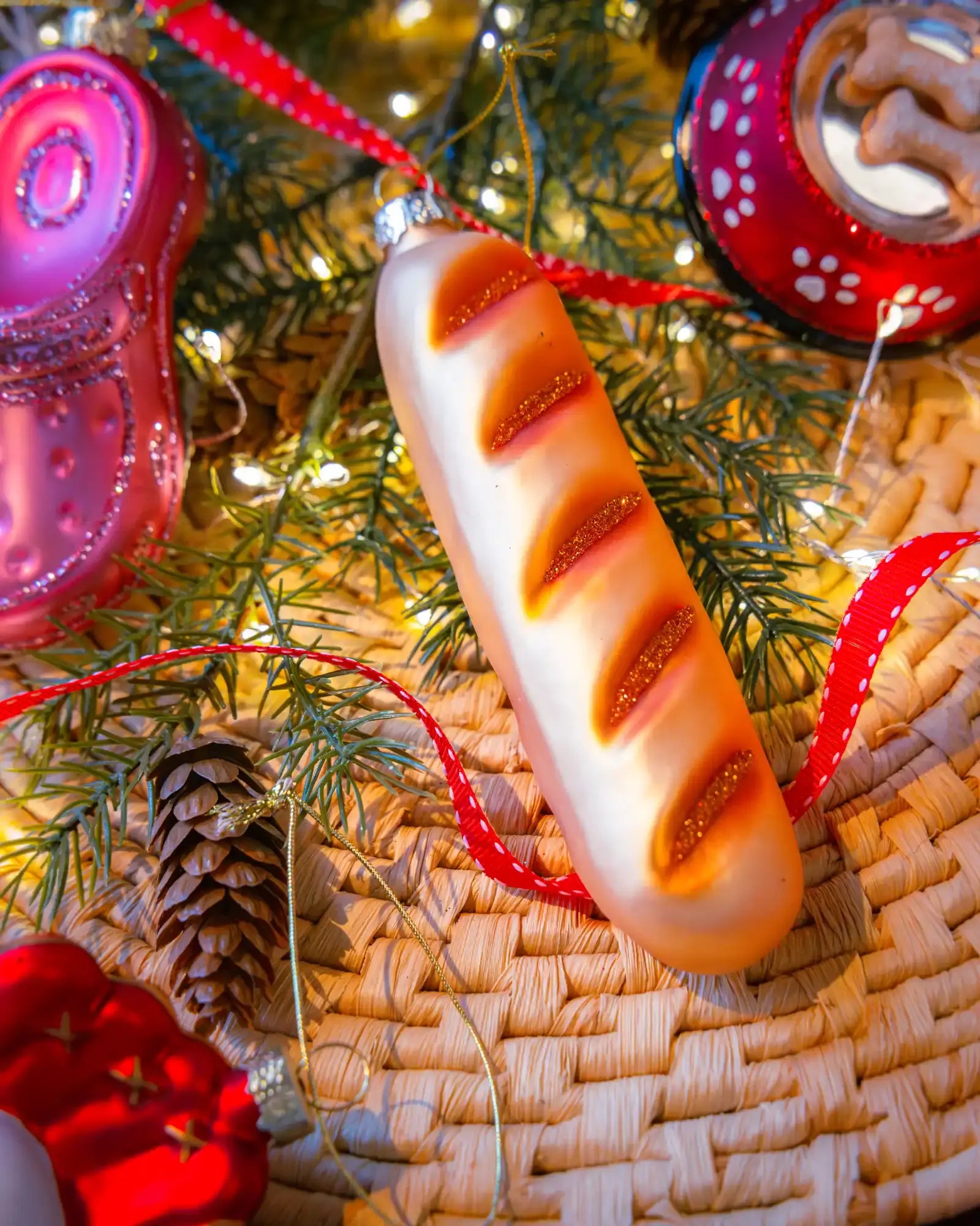 Chive glass baguette ornament in gold hanging on a holiday tree.