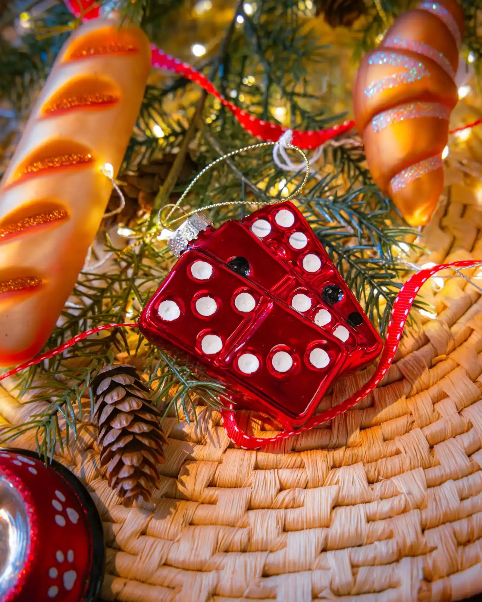 Chive glass dominoes ornament in red hanging on a holiday tree.