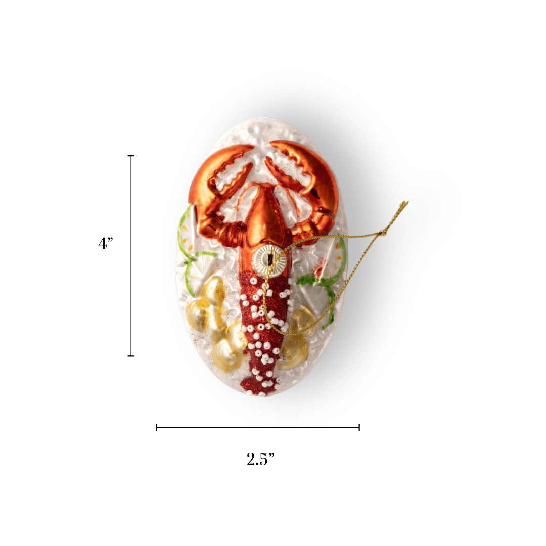 Chive glass lobster ornament on a plate with red claws and beaded garnish.