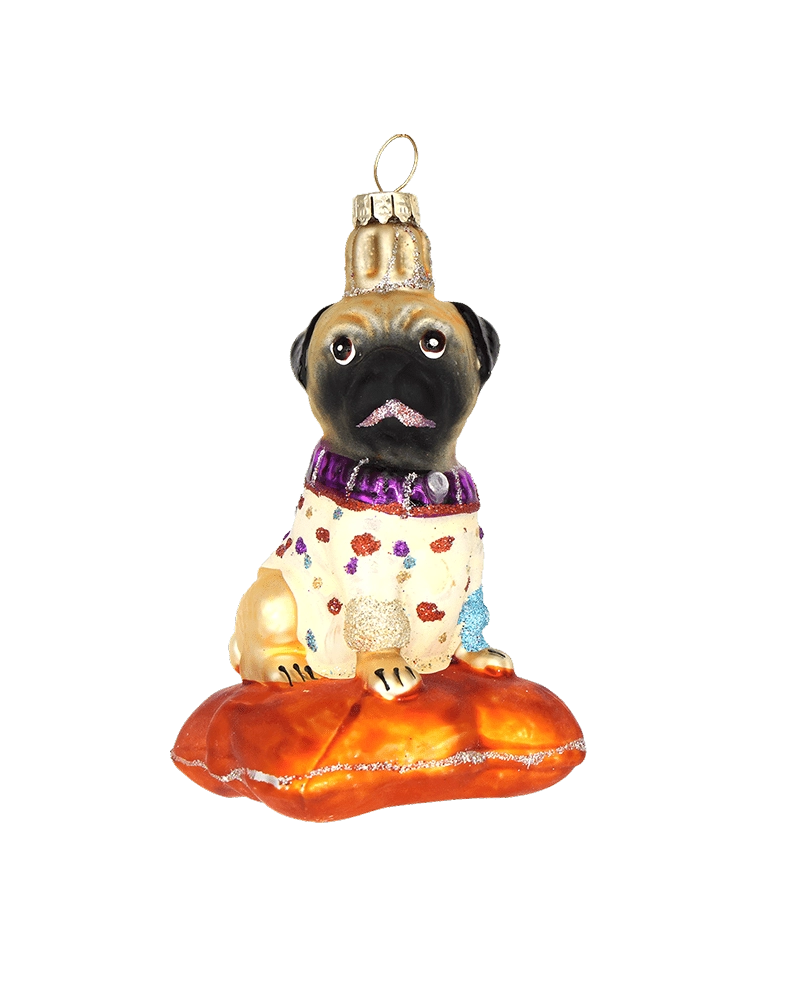 Chive glass pug ornament in a spotted sweater sitting on an orange cushion.