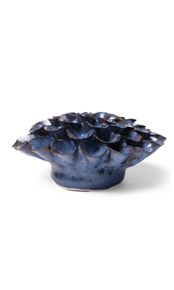 A small sculptural ceramic vessel with a ruffled, lotus-like top and a rounded base, shown on a clean white background. The glaze is predominantly deep blue with dark brown and black variation along the edges and highlights.