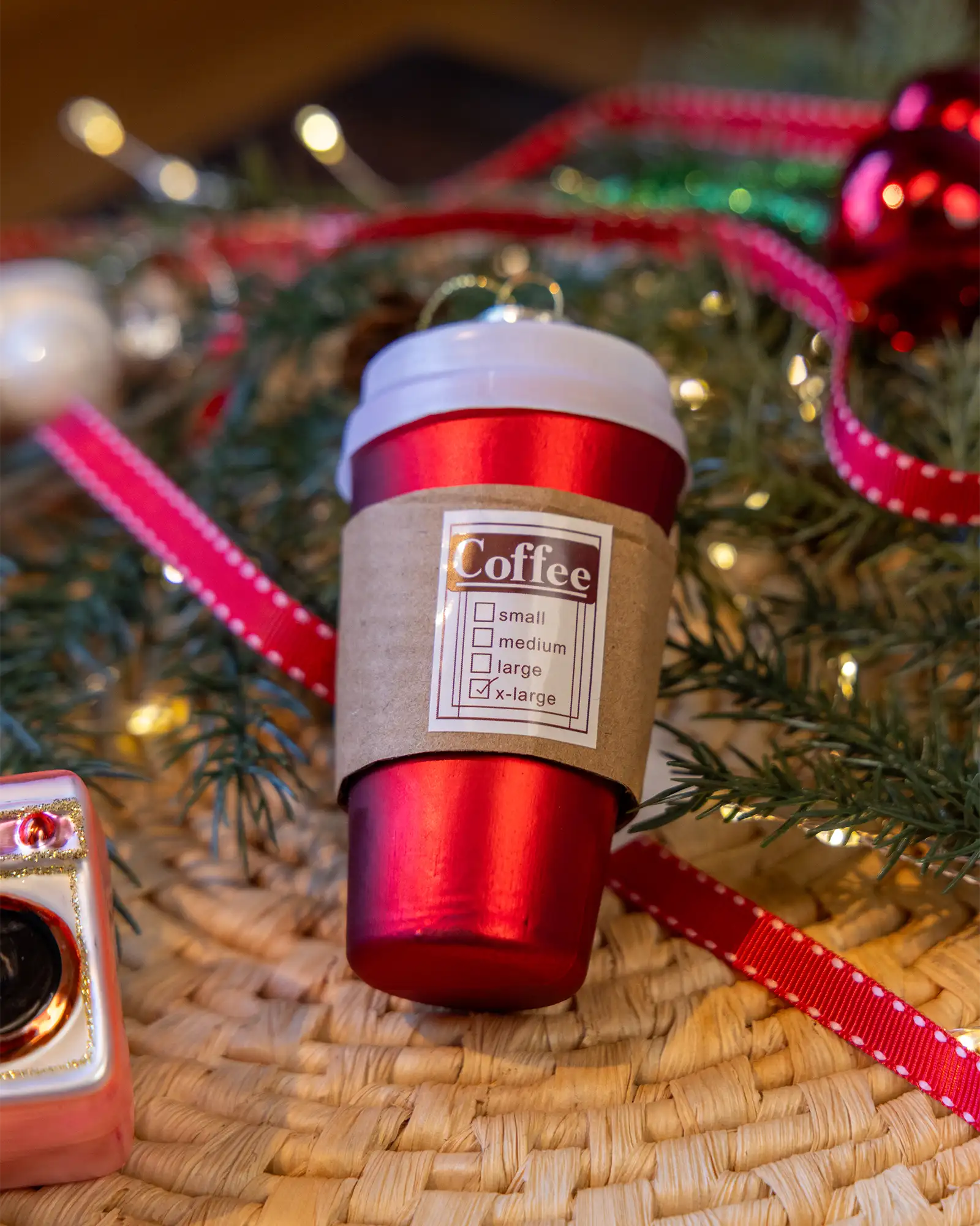 Red coffee cup ornament styled on a decorated Christmas tree
