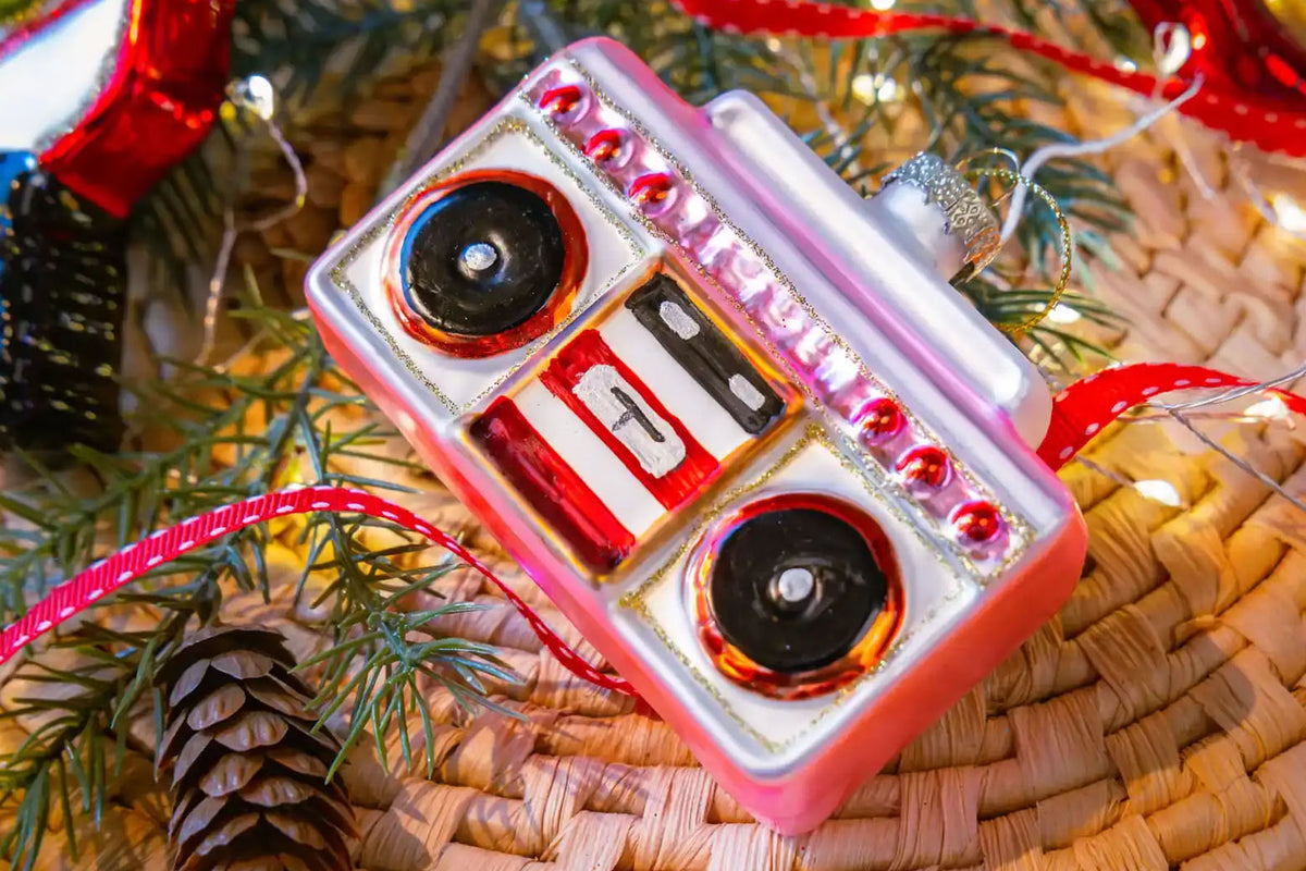 Chive glass boombox ornament in pink hanging on a holiday tree.