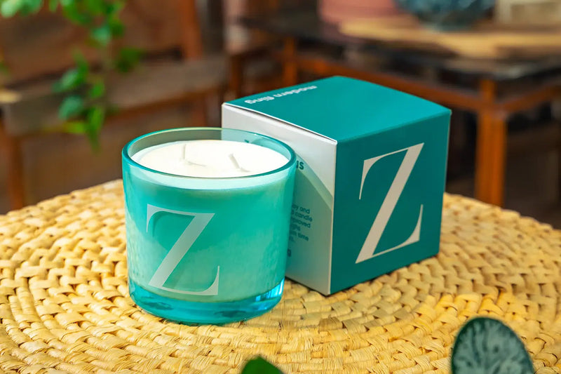 Chive Modern Fling coconut soy candle Z sitting on a straw placemat in a bright room.