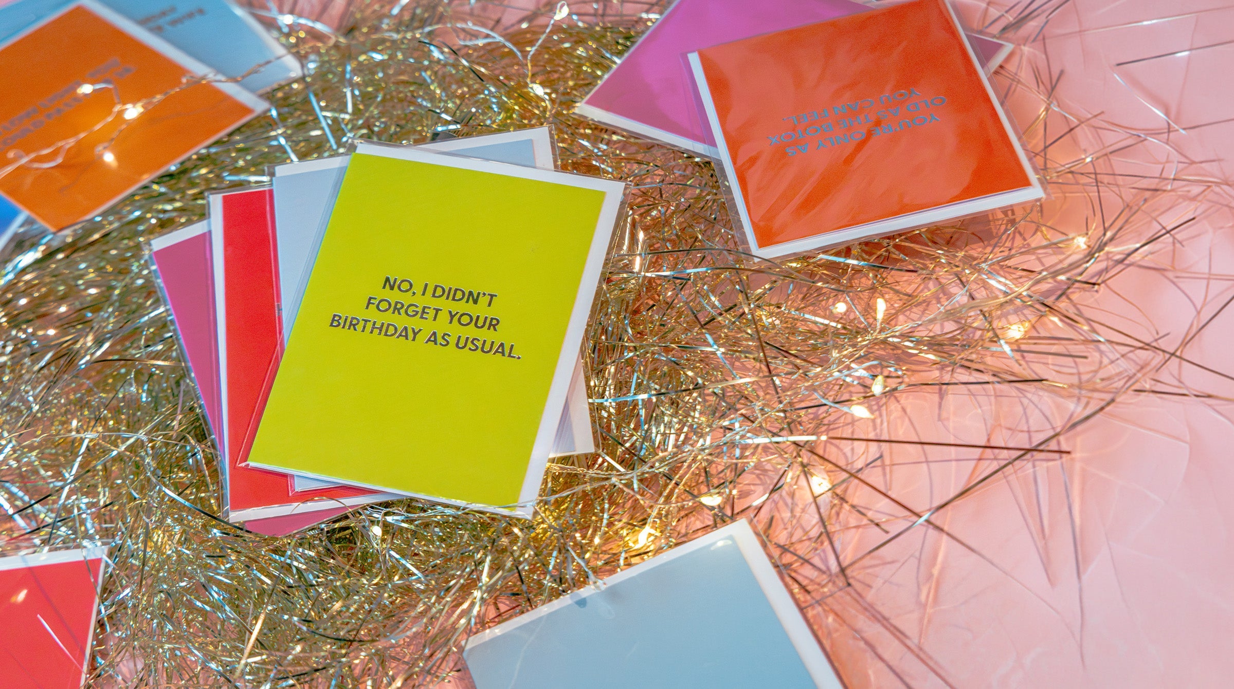 Funny birthday cards with illustrated jokes, fanned out on a table — by Chive Studio