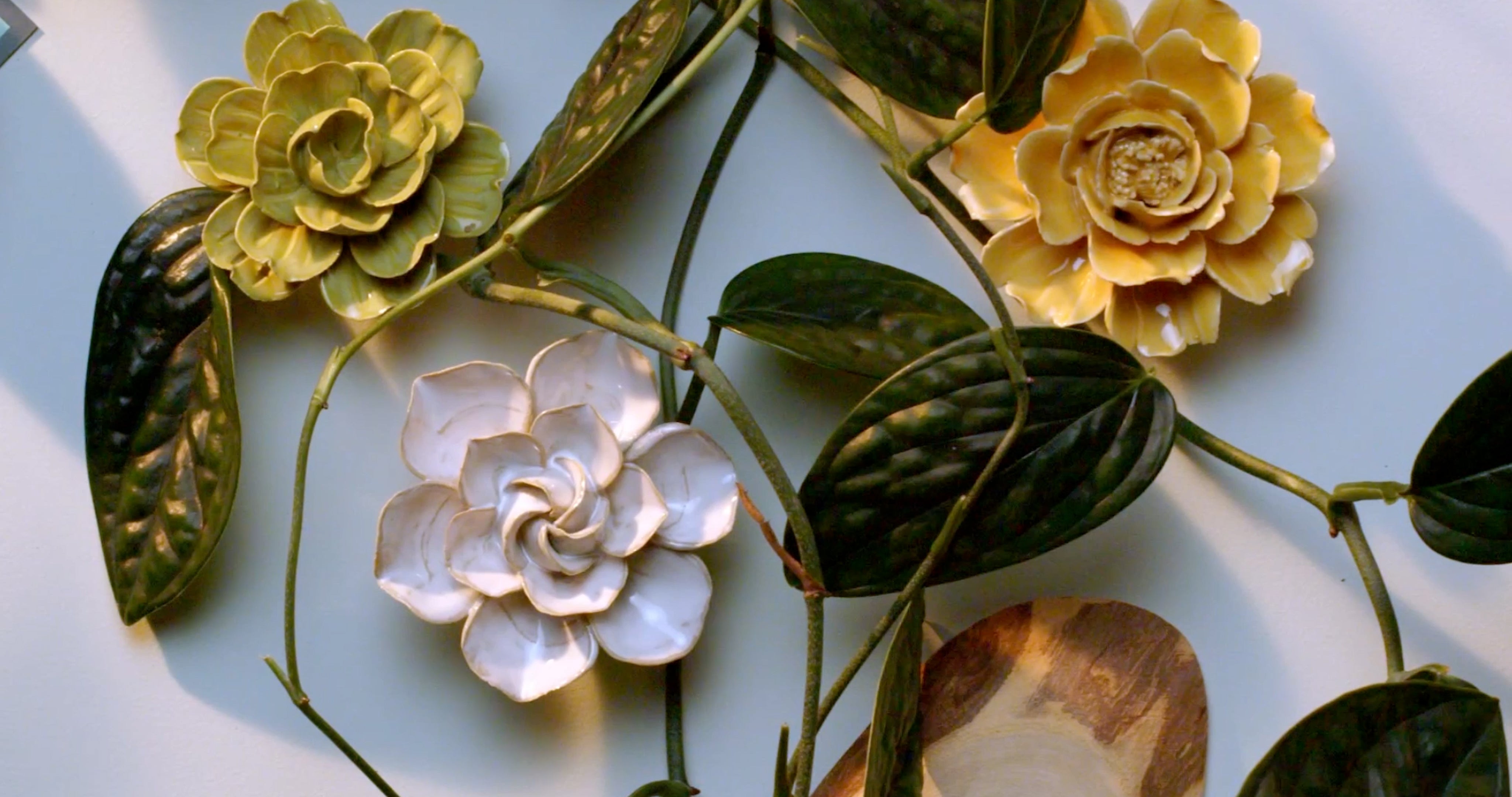 Ivory daffodil ceramic wall flower surrounded by jade green and fir green English Garden ceramic flowers on white background — handmade by Chive Studio Toronto
