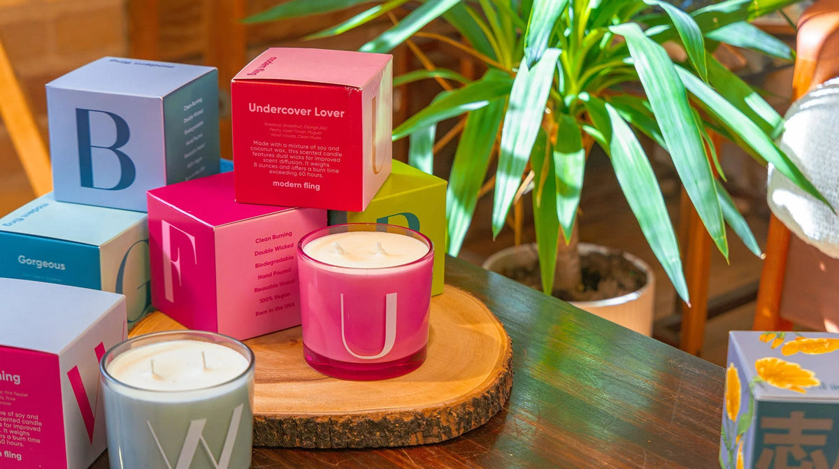 Two Chive Modern Fling teal nectar and pink sweet cheeks coconut soy medium candles styled with packaging boxed in a home setting.