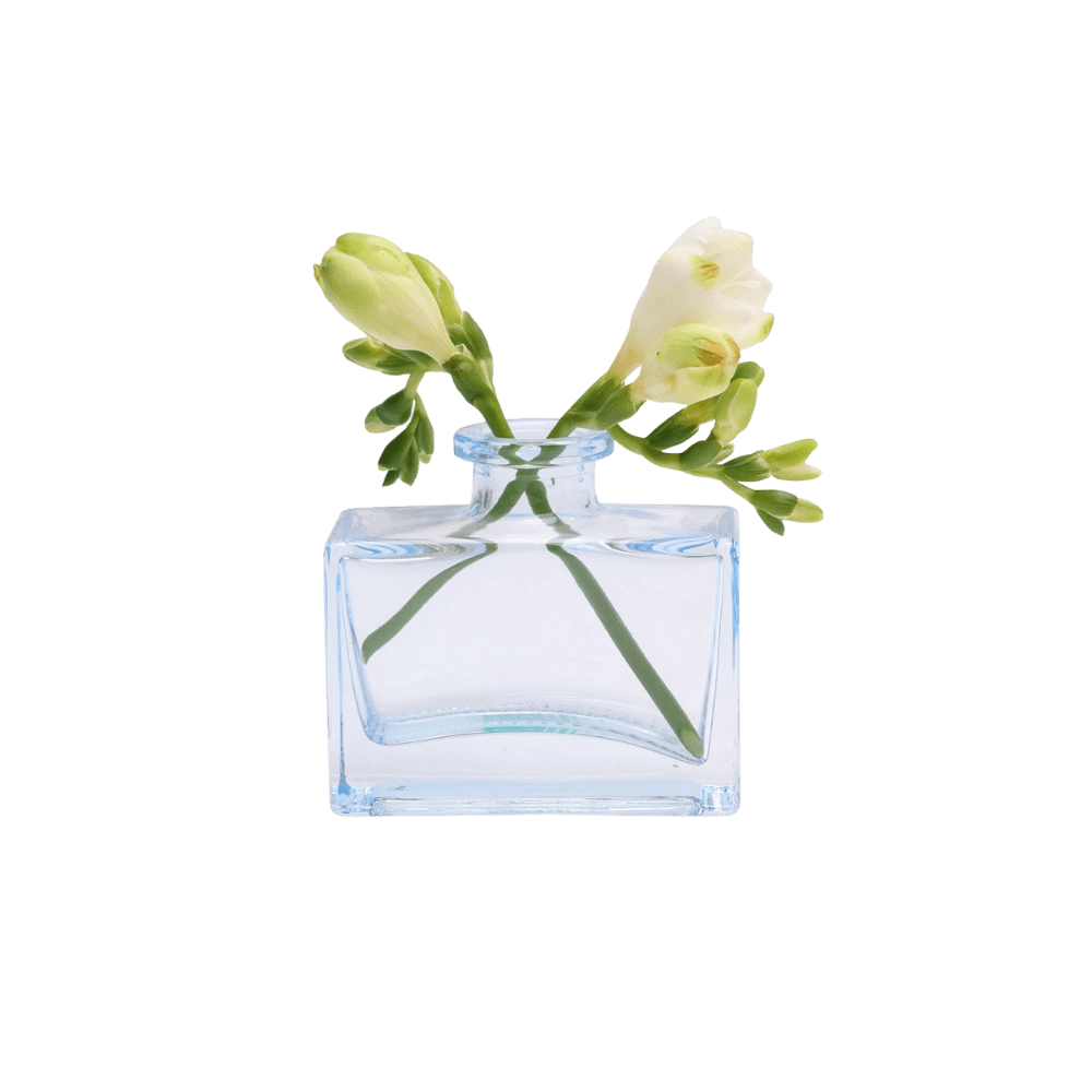Chive Loft glass bud vase in Light Blue holds white freesia blooms with trailing green buds.
