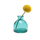 Chive Loft round glass bud vase in teal styled with a single yellow billy ball bloom.