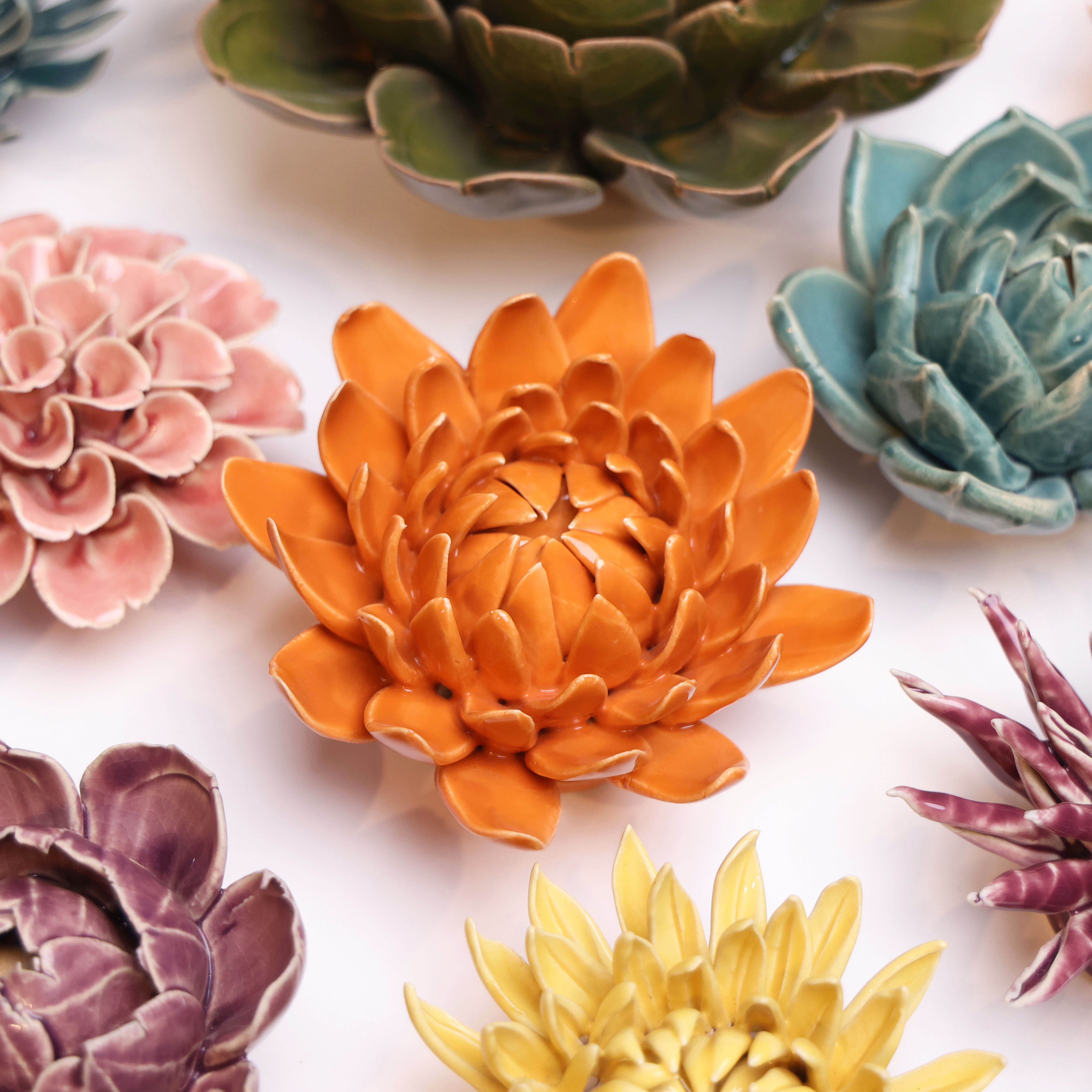 Orange Dahlia ceramic wall flower styled on a white table with other flowers — Chive Studio