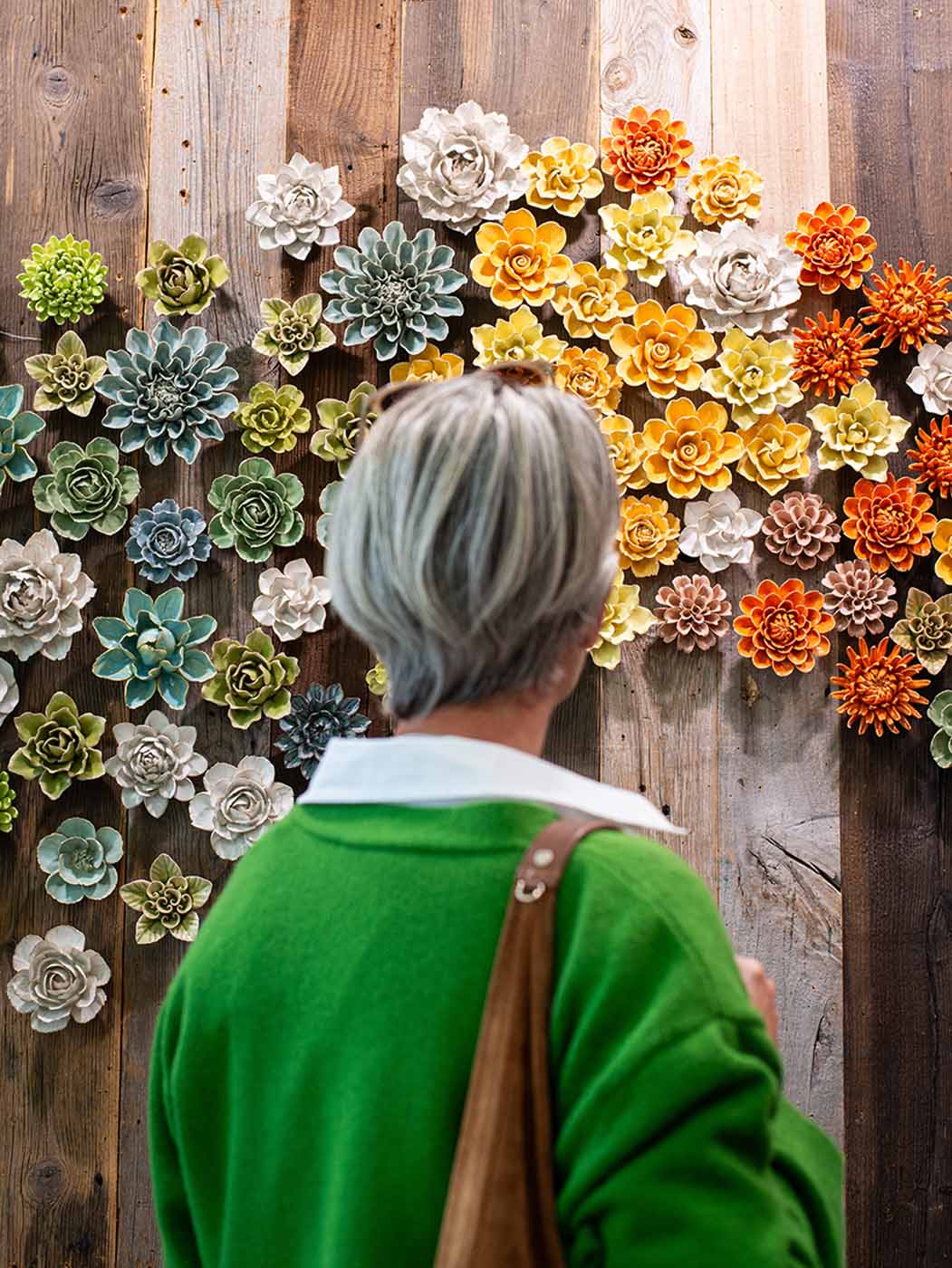 Chive Studio at Chelsea Flower Show displaying a wall of ceramic flowers in green, white, yellow, and orange.