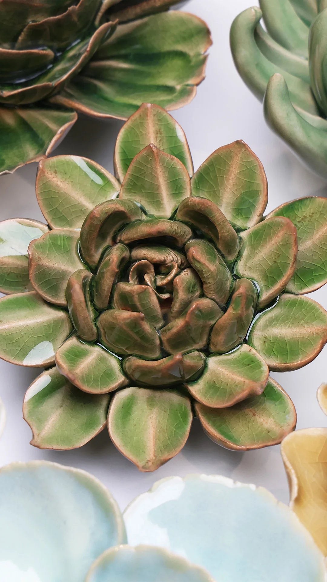 Avocado Green Firecracker Succulent ceramic wall flower styled on a white table with other flowers — Chive Studio