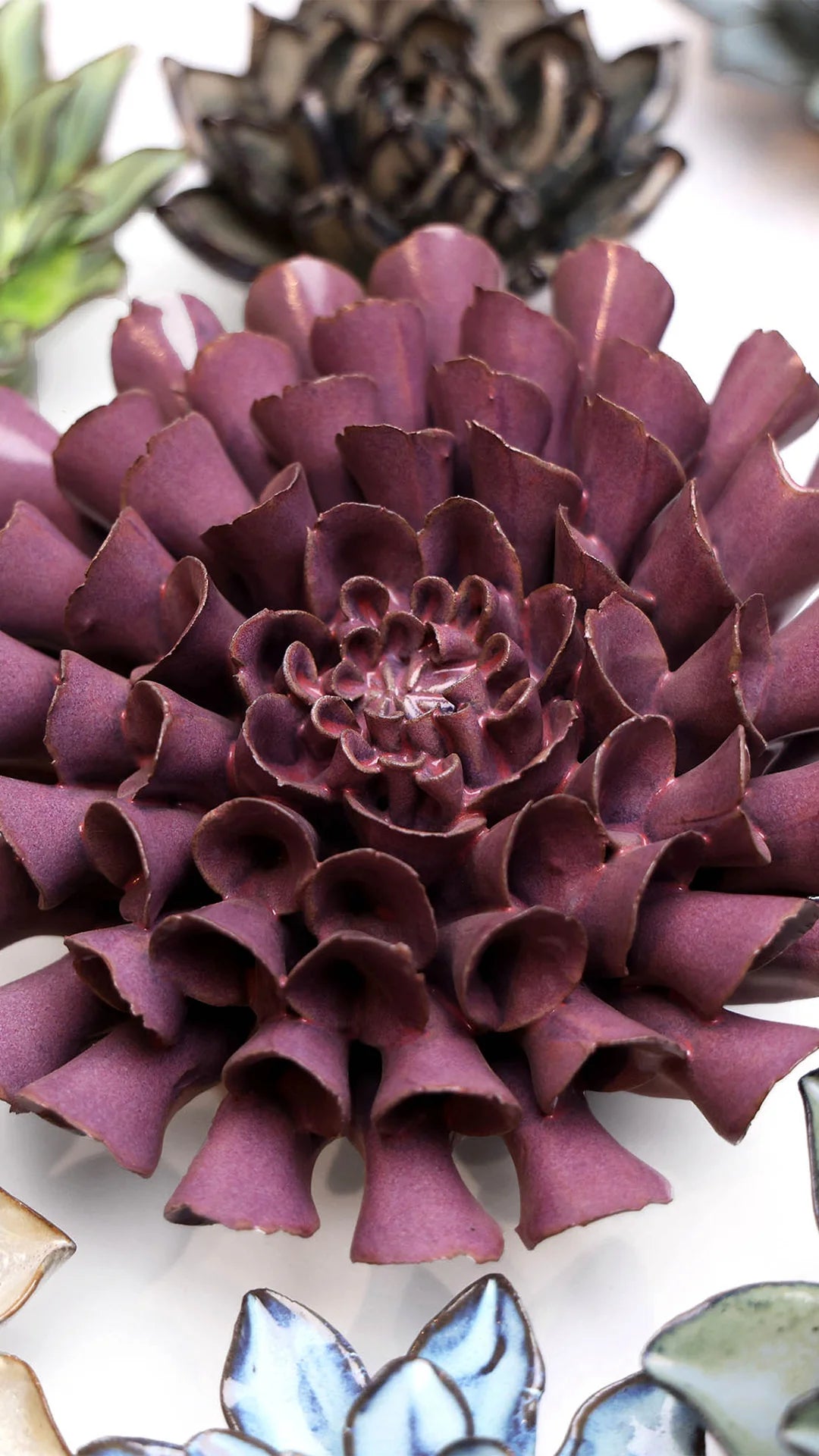Violet Blue Dahlia ceramic wall flower styled on a white table with other flowers — Chive Studio