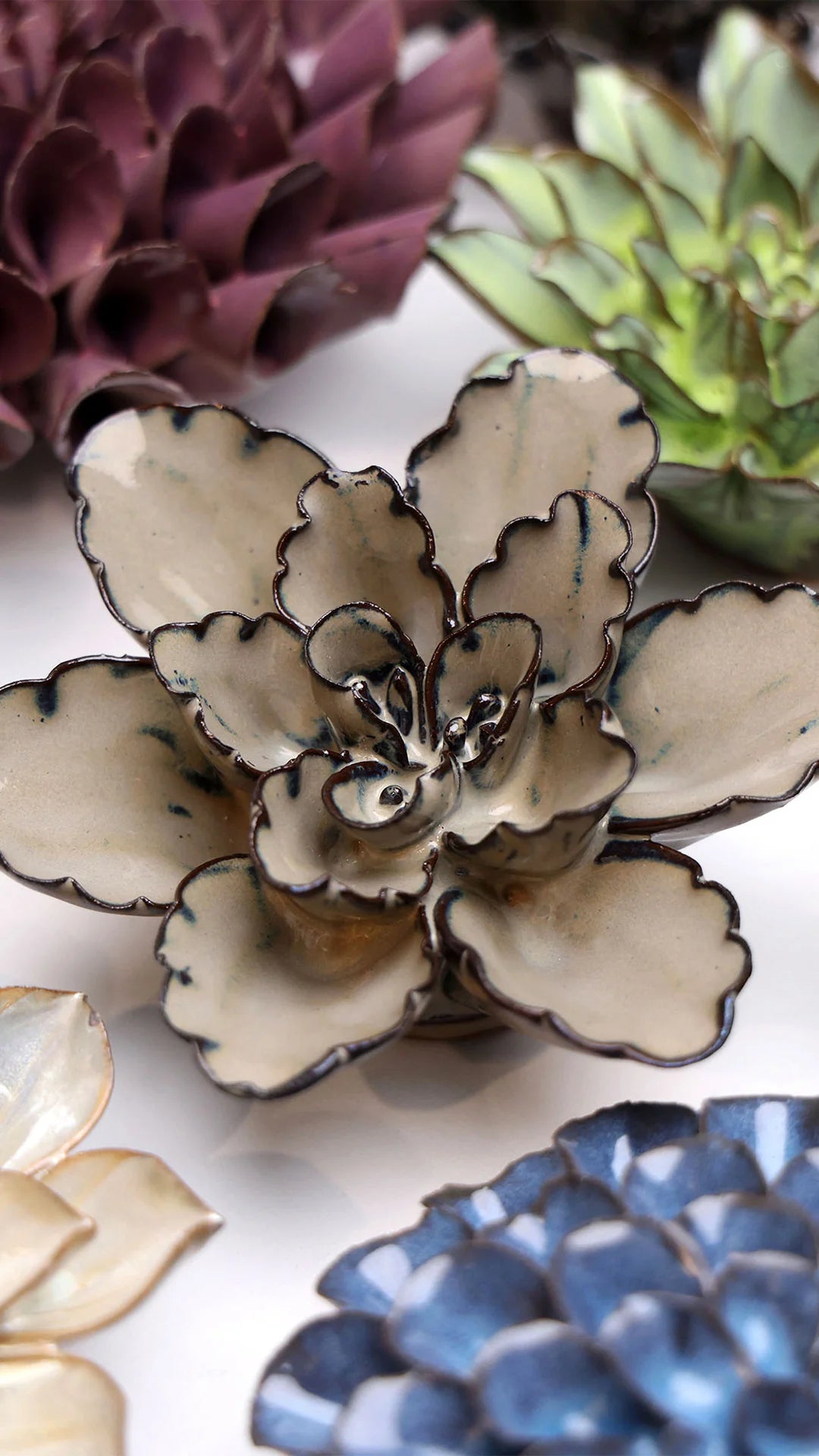 Latte Empress Lotus ceramic wall flower styled on a white table with other flowers — Chive Studio