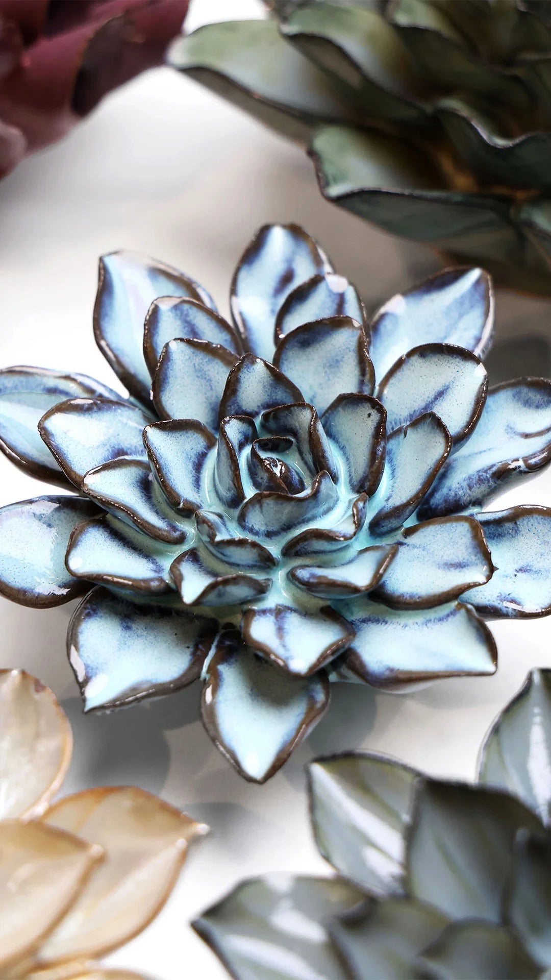 Blue Alpine Aster ceramic wall flower styled on a white table with other flowers — Chive Studio