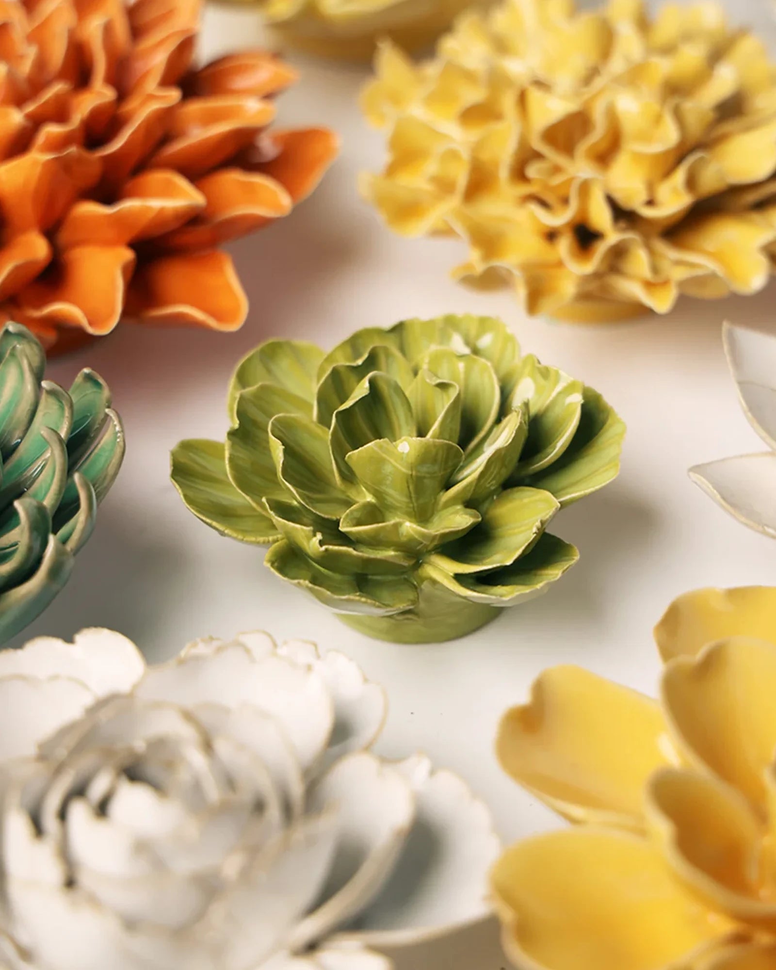Close-up of the Chive February Birth Flower Primrose chartreuse ceramic flower among assorted Chive ceramic flowers.