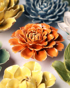 Close-up of the Chive October Birth Flower Marigold fiesta orange ceramic flower among assorted Chive ceramic flowers.