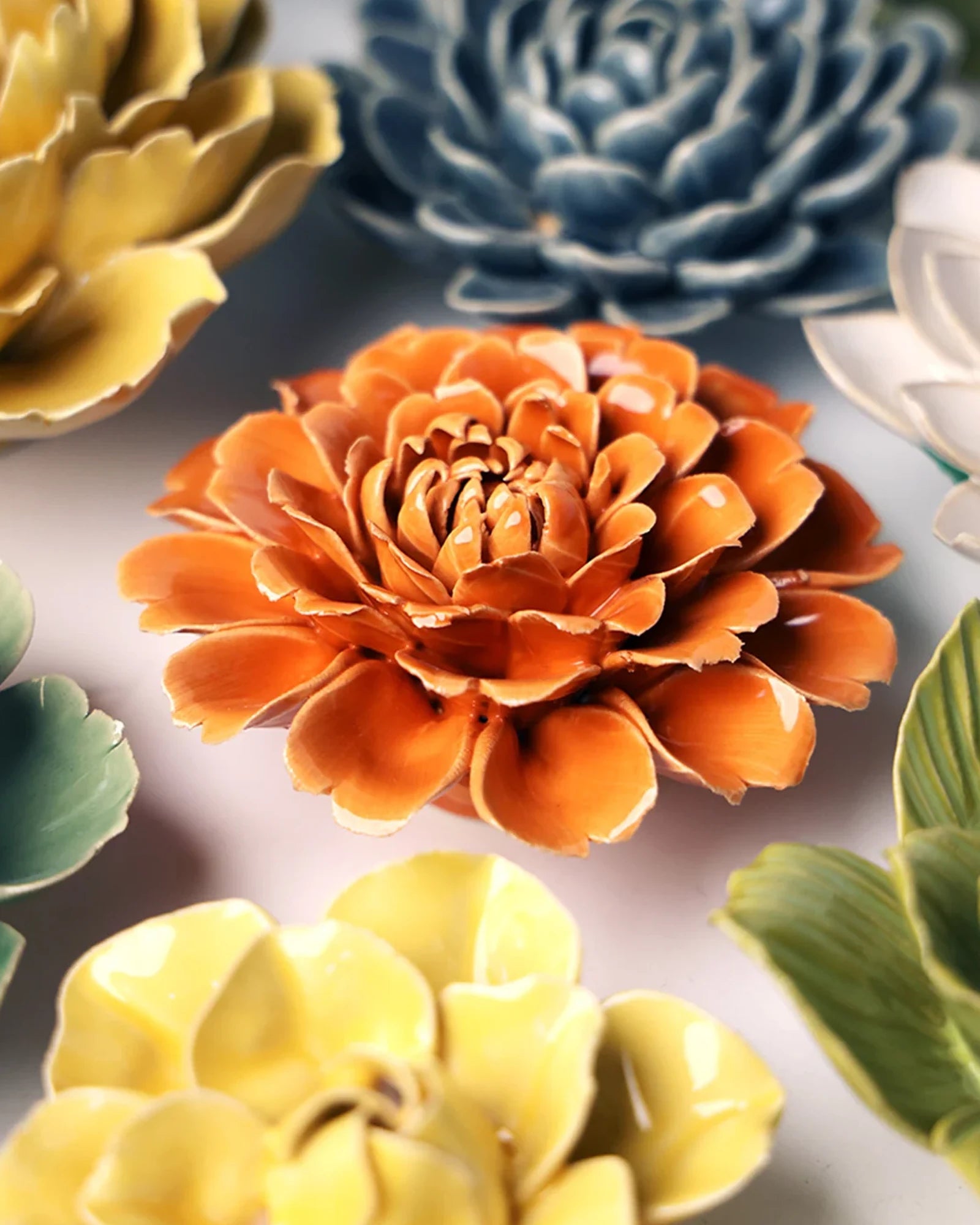Close-up of the Chive October Birth Flower Marigold fiesta orange ceramic flower among assorted Chive ceramic flowers.