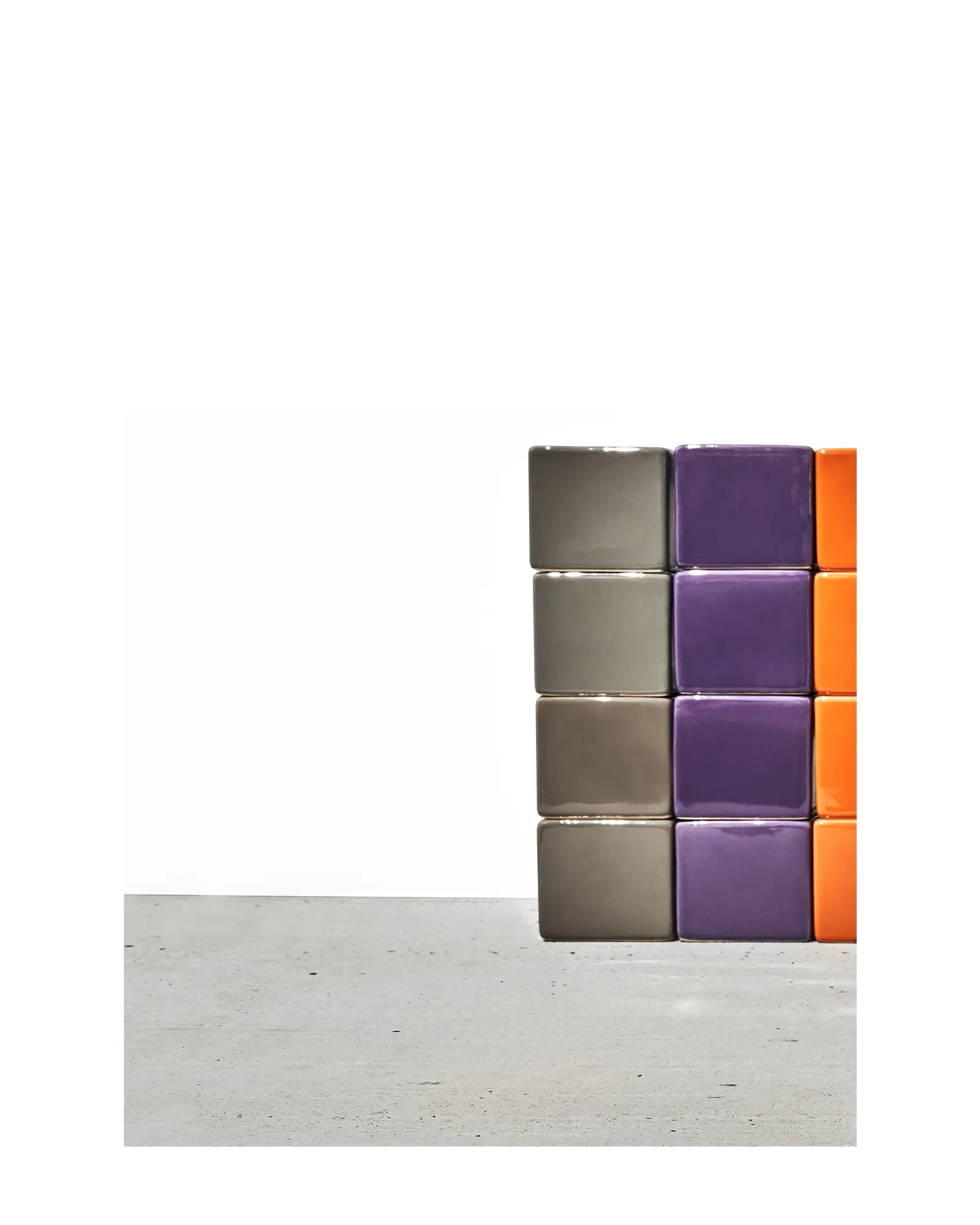 Chive Cube Saucer ceramic planters stacked in columns of grey, purple, and orange on a concrete floor.