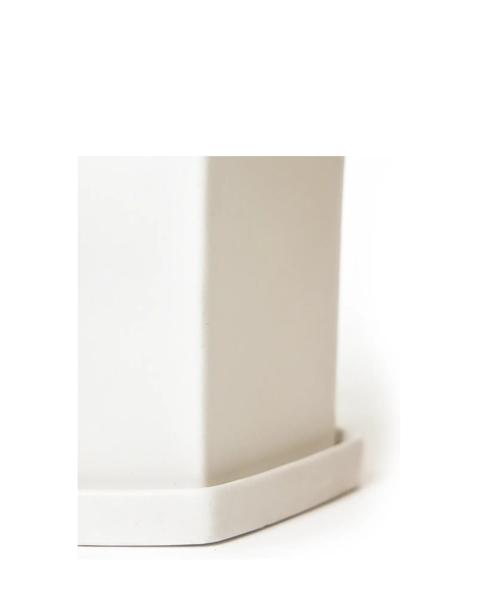 Close-up of the flat panelled surface and hexagonal saucer on a Chive Hexi white ceramic pot.