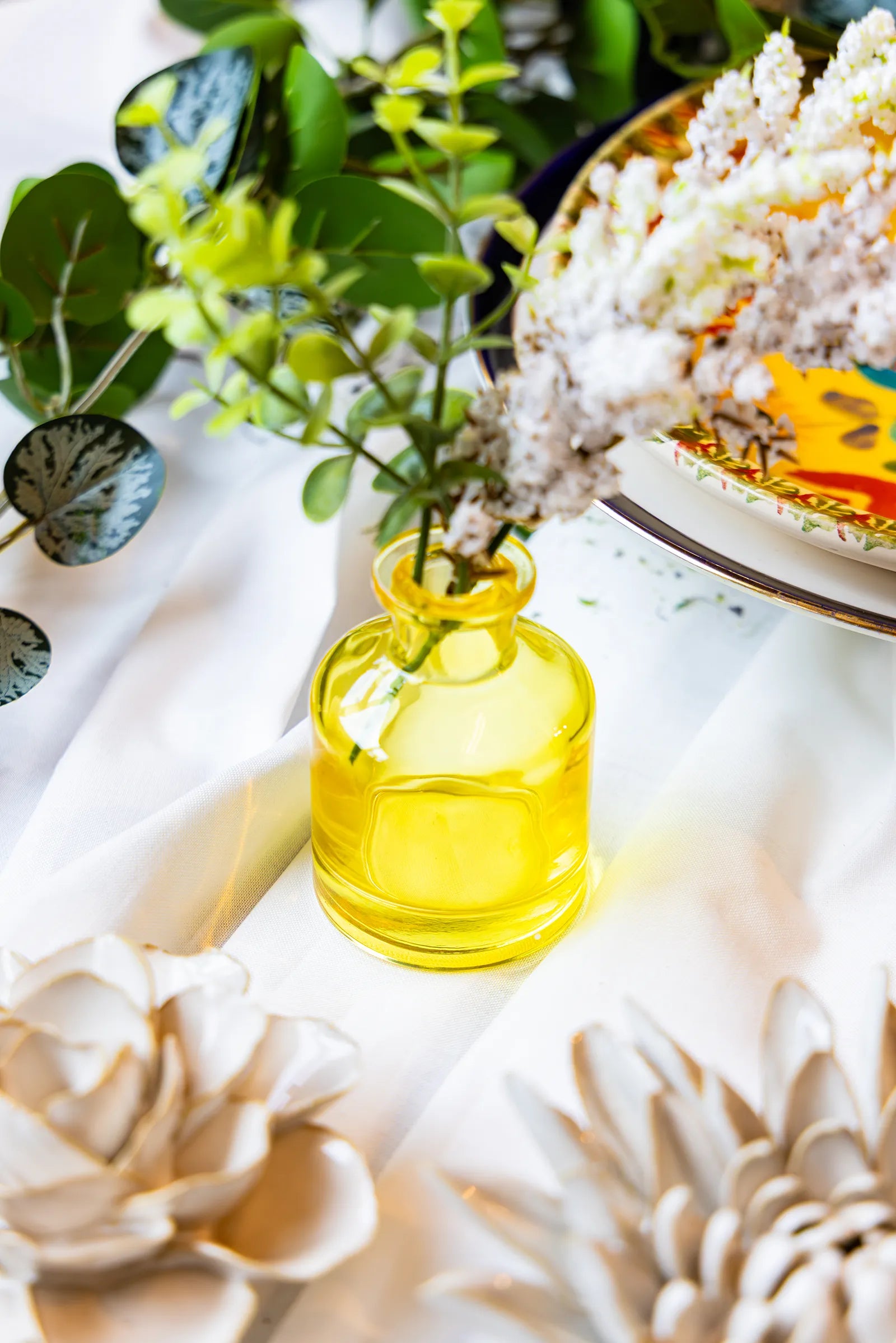 Close up of a wedding tabletop arrangement with a Chive Loft yellow glass bud vases holding white flowers.