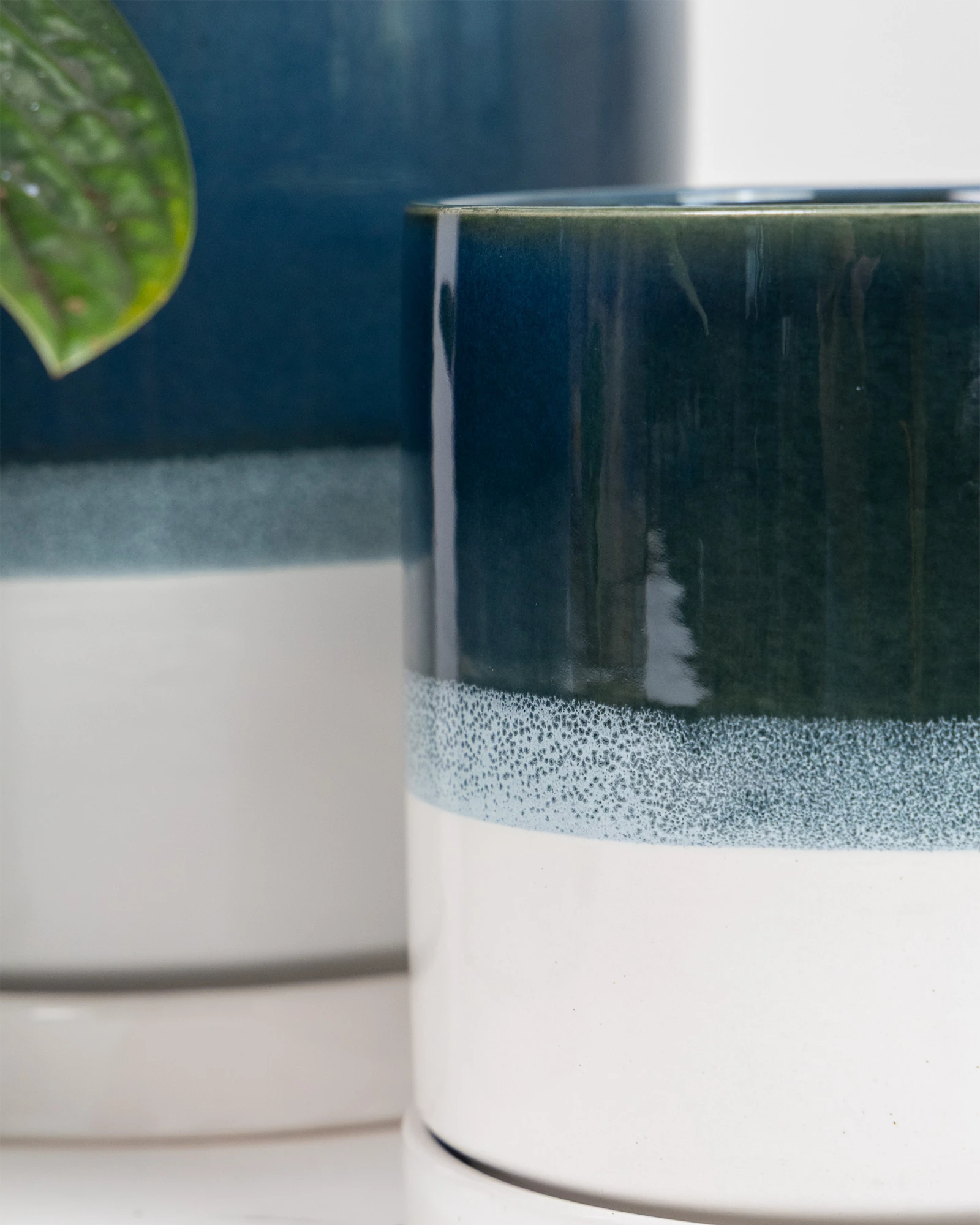 Close up of two Chive Minute green blue ceramic planter pots showing the color gradient and saucer detail.