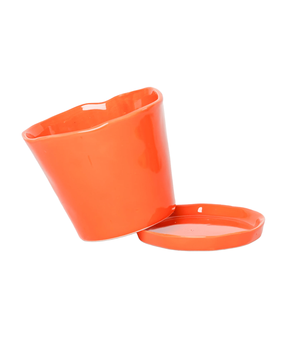 Close up of Chive Tika orange ceramic small plant pot with drainage tilted to show the detachable saucer, 
