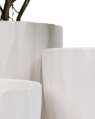 Close-up of three Chive Virago E white porcelain pots in large, medium, and small showing the vertical waves texture. 
