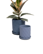 Two Chive Virago F blue grey porcelain pots with drainage and detachable saucers styled with a plant in small and medium.