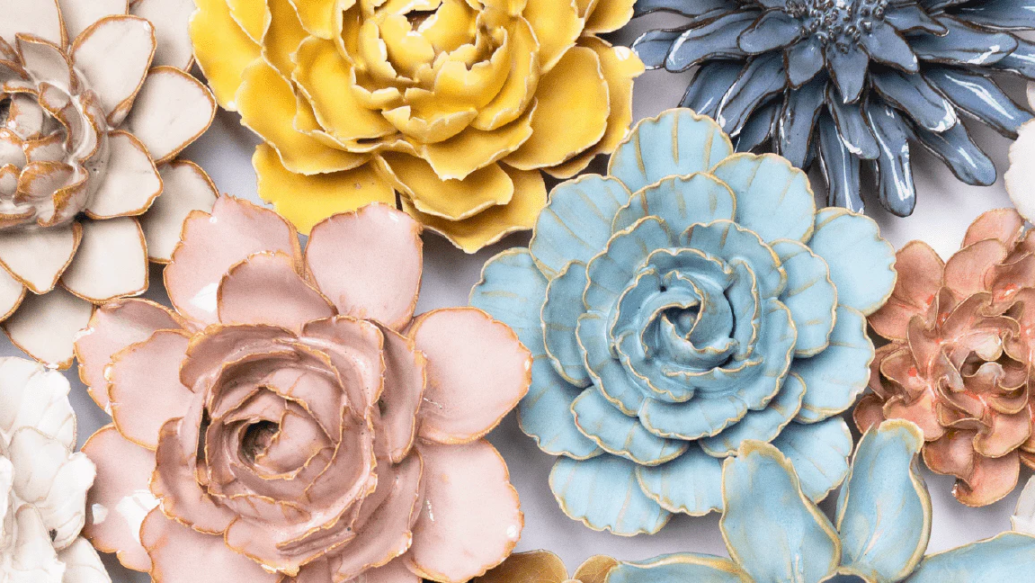 Blue, pink, oatmeal, white and yellow mixed ceramic wall flowers arranged on white background — Chive Studio