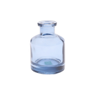 Chive Loft apothecary glass bud vase in medium blue with a tall cylindrical silhouette and wide lip.