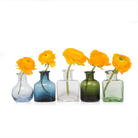 Chive Loft glass bud vase set in five shapes and colors, each holding a single orange ranunculus.
