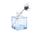 Chive Loft cube glass bud vase in light blue styled with a single blue thistle stem.