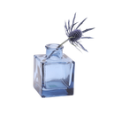 Chive Loft cube glass bud vase in medium blue styled with a single blue thistle stem.