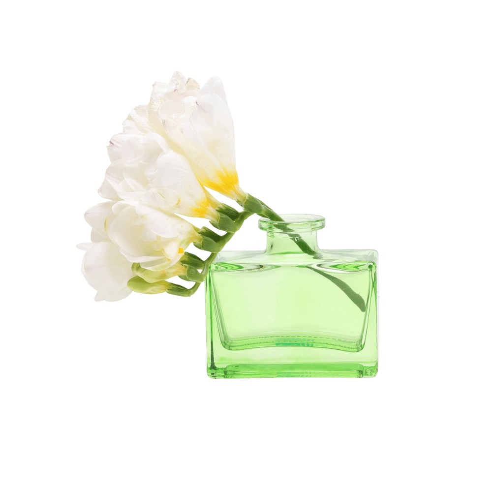 Chive Loft square glass bud vase in green holding freesia blooms, shown from a side angle.