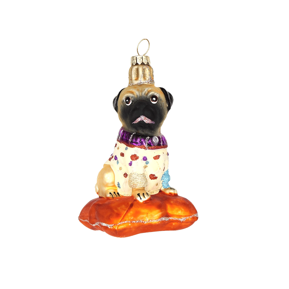 Chive glass pug ornament in a spotted sweater sitting on an orange cushion.