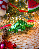 Chive glass stegosaurus ornament in green hanging on a holiday tree.