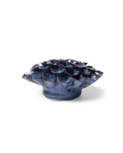 A small sculptural ceramic vessel with a ruffled, lotus-like top and a rounded base, shown on a clean white background. The glaze is predominantly deep blue with dark brown and black variation along the edges and highlights.